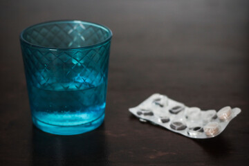 Blue glass with water and medicine on a wooden table