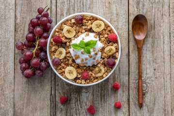Oatmeal with raspberries, grapes and banana on a wooden background. Breakfast porridge with berries.