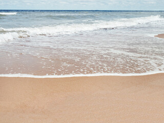 Sea coast with soft surf. Sandy beach. Summer vacation on seaside.