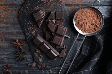Flat lay composition with delicious dark chocolate on black wooden table