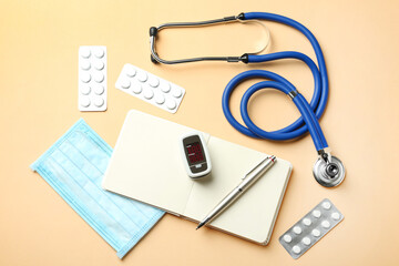 Flat lay composition with fingertip pulse oximeter and medical items on orange background