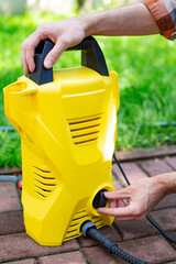 Using a compact pressure washer in the garden, close-up.