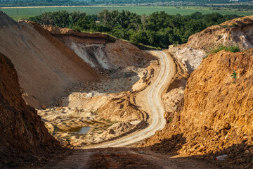 road through a sand pit against a forest background