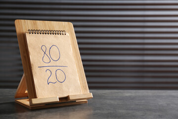 Notebook with 80/20 rule representation on grey stone table, space for text. Pareto principle...