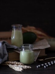 Avocado Smoothies Rustic Setting. Avocado Milkshake on Dark Background with Copy Space. Rustic Avocado Juice.