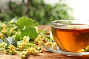 Cup of tea and linden blossom on wooden table, closeup