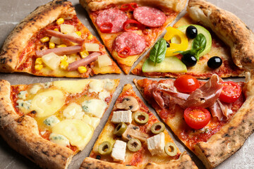 Slices of different delicious pizzas on table, closeup