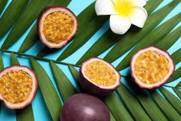 Passion fruits (maracuyas), flower and palm leaf on light blue background, flat lay