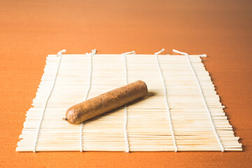 Fragrant cigar on white bamboo mat.