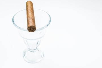 Thick cigar from twisted sheets in glass bowl with white background.