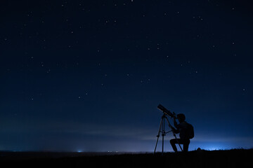 Human silhouette and telescope, a woman looks through a telescope at the starry sky. Night sky, stars, long exposure, astronomy