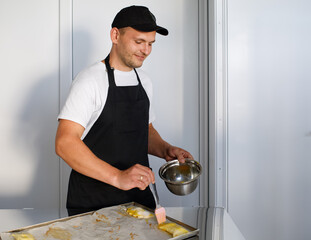 A young baker greases the dough before baking