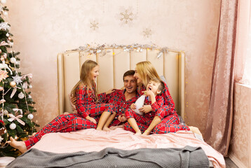 Happy family having fun at Christmas time in bedroom.