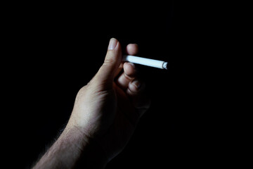 male hand holding cigarette dark background