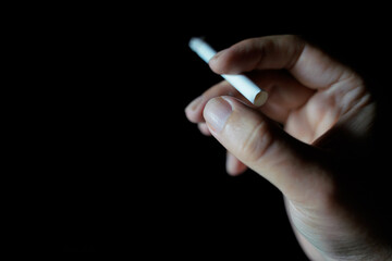 male hand holding cigarette dark background