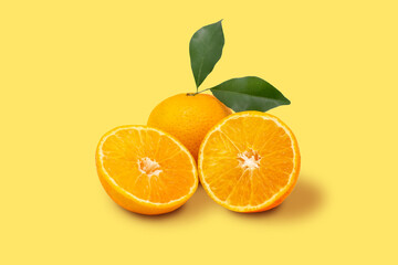Orange fruit and ripe half of orange fruit on yellow background