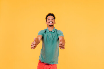 Good-humoured laughing man posing with thumbs up. Studio photo of glad stylish guy isolated on...