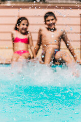 Obraz na płótnie Canvas Defocused children splashing water at the edge of the pool