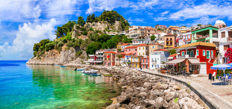 Parga town Greece colorful houses on the waterfront, scenic coastal street curve by turquoise sea and rocks. Authentic Mediterranean village in Epirus Riviera. Scenic landscape with no people.