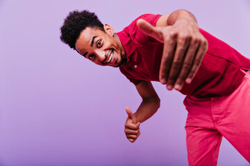 Excited black male model dancing in studio. Funny emotional man in red t-shirt looking to camera...
