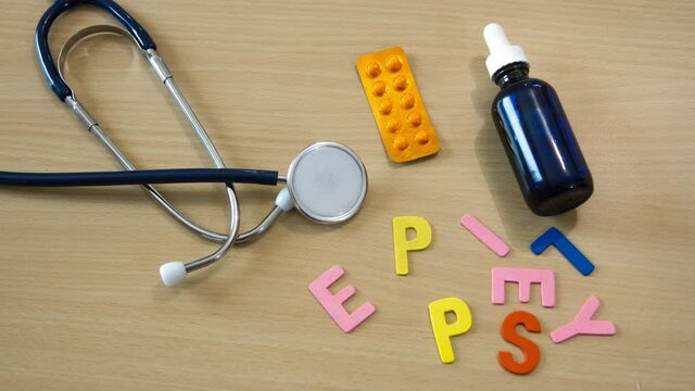 stop motion time lapse of word with colorful epilepsy letters on a table with a stethoscope and moving medicines