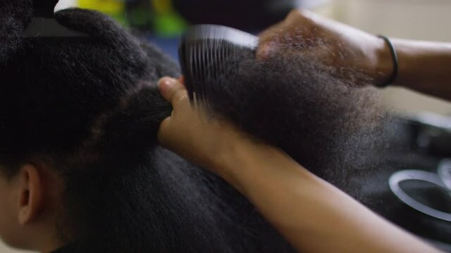 Hands of a female combing through long afro hair