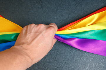 male hand squeezing lgbt rainbow flag using how to celebrate homosexual, gay, lesbian and concept