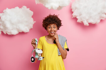 Coming maternity. Positive pregnant woman in third trimester poses with mobile and bodysuit for...