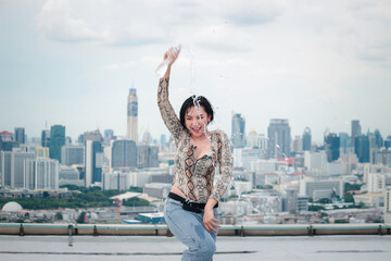 Fototapeta na wymiar Asian attractive sexy dancer women dancing during pour water form the bottle on rooftop with skyscraper city view, hip hop street dance