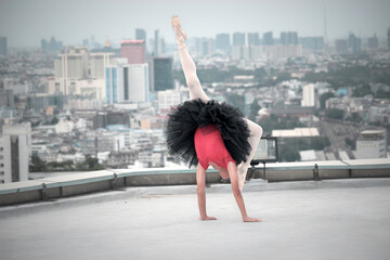 Asian gymnast doing a somersault, ballerina dancer girl practicing ballet dancing on rooftop with...