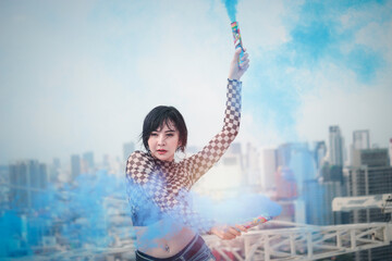 Fototapeta na wymiar Asian attractive sexy dancer women dancing with colored smoke bomb on rooftop with skyscraper city view, hip hop street dance
