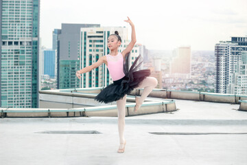 Asian ballerina dancer girl practicing ballet dancing on rooftop with skyscraper city view, adorable child dancing in ballet