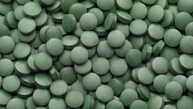 rotating Spirulina, chlorella supplement pills close up, macro shot
