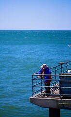 man sitting and fishing on the pier