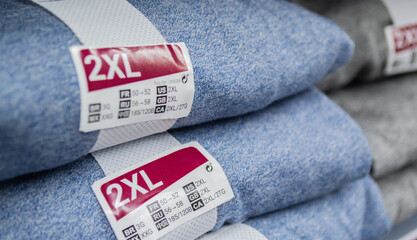  A stack of blue and gray clothing with the size label 2XL. Selective focus