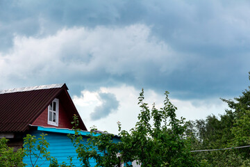 Village house roof and gloomy rain clouds