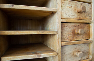 An old, battered chest of drawers made of textured wood. Empty, with drawers
