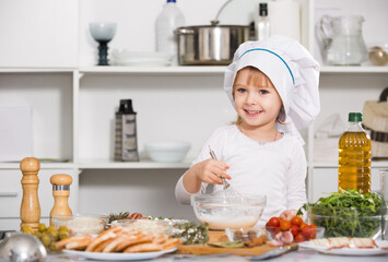 Young girl is satisfied of cooking sauce in the kitchen at home.