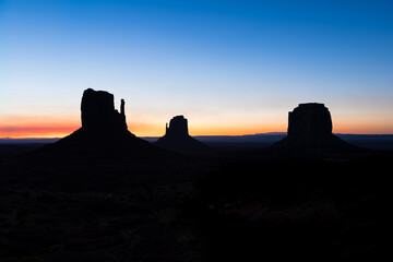 View of Monument Valley buttes silhouette and horizon during blue hour dawn night with sunrise colorful light in Arizona in sky