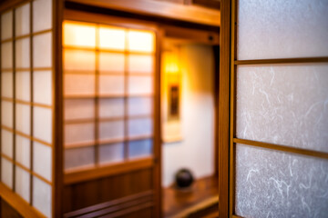 Traditional and modern Japanese house ryokan hotel room with wooden sliding paper shoji doors and alcove in blurry background - obrazy, fototapety, plakaty