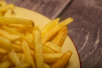 French fries in a round plate on a homespun cloth with a rough texture. Close up.
