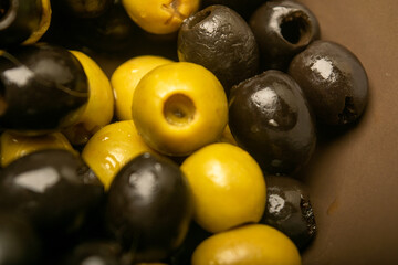 Green olives and black olives scattered on sacking with rough texture. Close up.