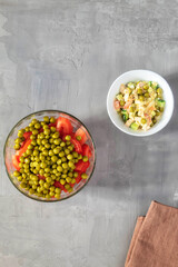 Two summer salads of fresh vegetables in plates on a gray background