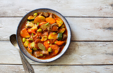 Beef meat and vegetables stew in a  plate on natural wooden table