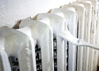 Old cast iron radiator painted with white paint, selective focus. Repairs.