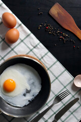 Culinary background with fried eggs in a pan, eggs, peas pepper on a white checkered tablecloth. Culinary concept. the process of cooking eggs. Illustration for cookbook.