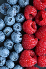 Background with ripe and bright raspberries and blueberries. Berry mix. Heart-shaped raspberries. Proper and healthy nutrition. Design for advertising and books of juices, jams, dessert. Ingredient.