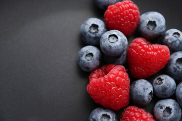 Background with ripe and bright raspberries and blueberries. Berry mix. Heart-shaped raspberries. Proper and healthy nutrition. Design for advertising and books of juices, jams, dessert. Ingredient.