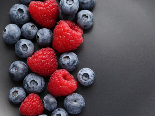Background with ripe and bright raspberries and blueberries. Berry mix. Heart-shaped raspberries. Proper and healthy nutrition. Design for advertising and books of juices, jams, dessert. Ingredient.