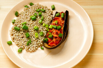 Green buckwheat with baked eggplant with tomato and garlic on a plate.